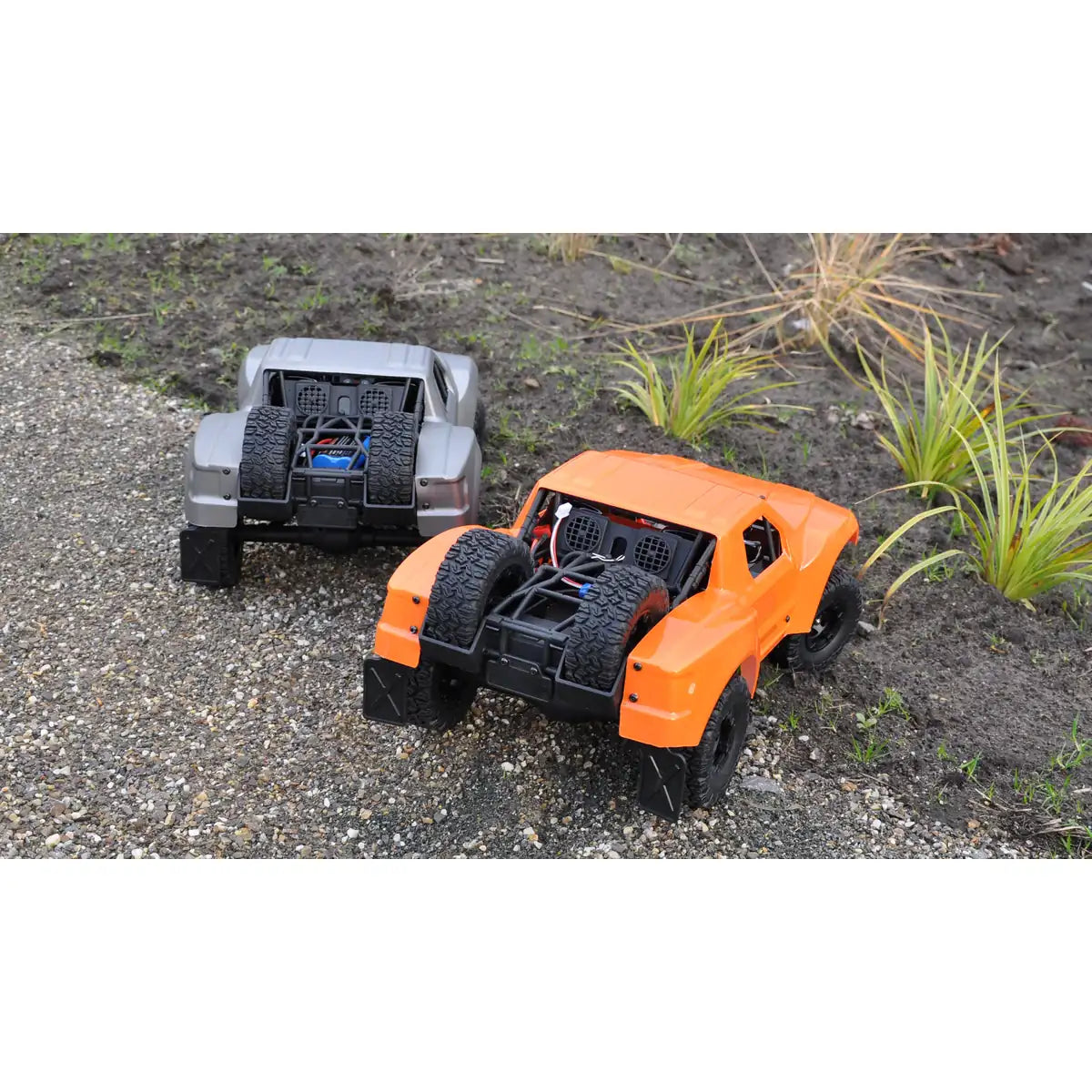 Amewi Short Course Truck SC12 brushed Silber 22430 im Maßstab 1:12 Offroad RTR – Draufsicht zwei RC-Trucks auf Kies und Erde